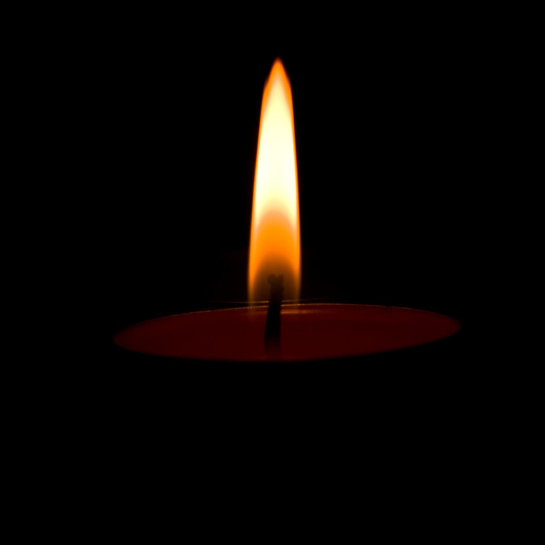 single candle flaming in the darkness